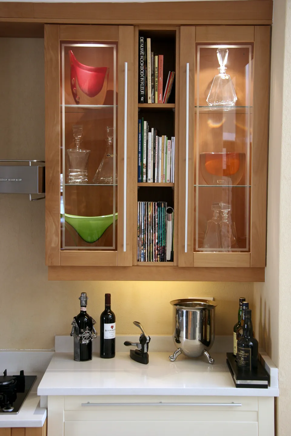 Lit glass display cabinet above a cookbook shelf
