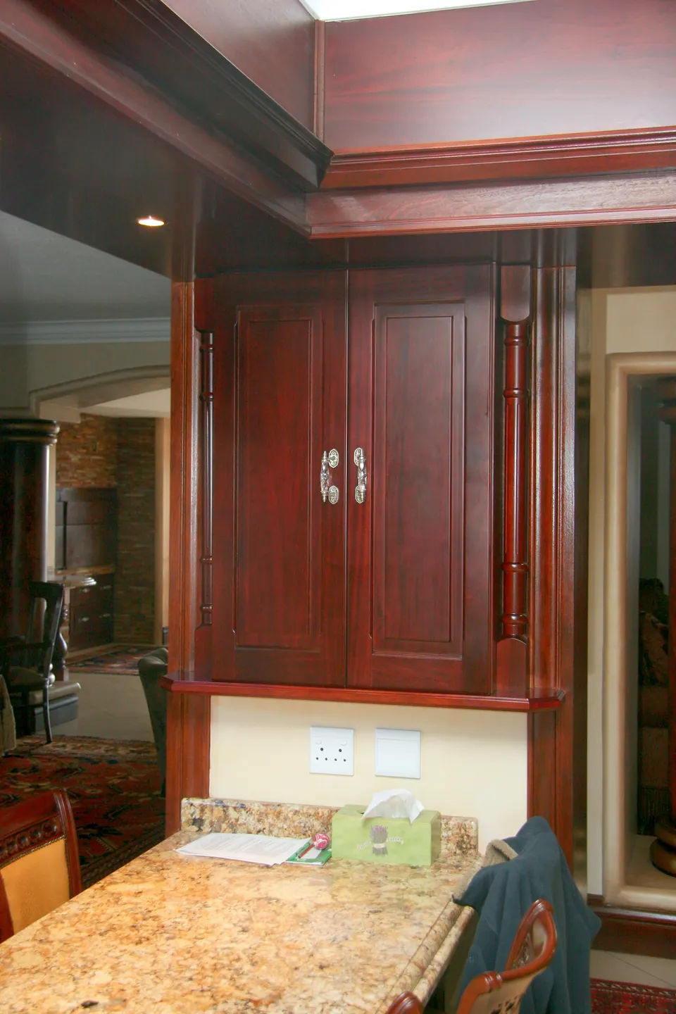 Raised-panel wall cabinet framed by turned pilasters and a deep cornice