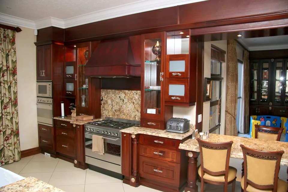 Range wall with a stone splashback, glazed display cabinets and a breakfast nook