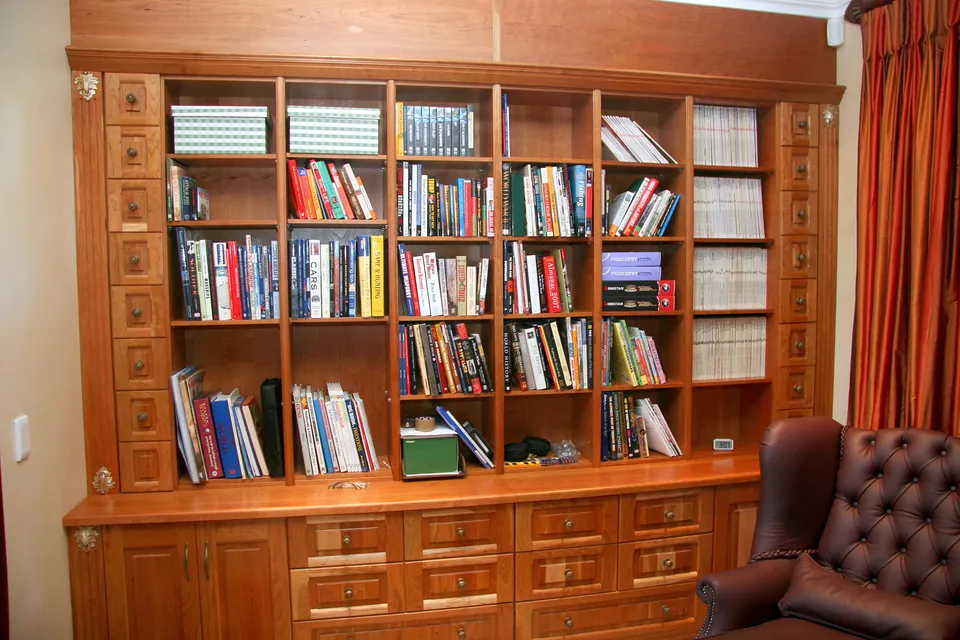 Library wall in solid cherry with open shelving over a bank of drawers