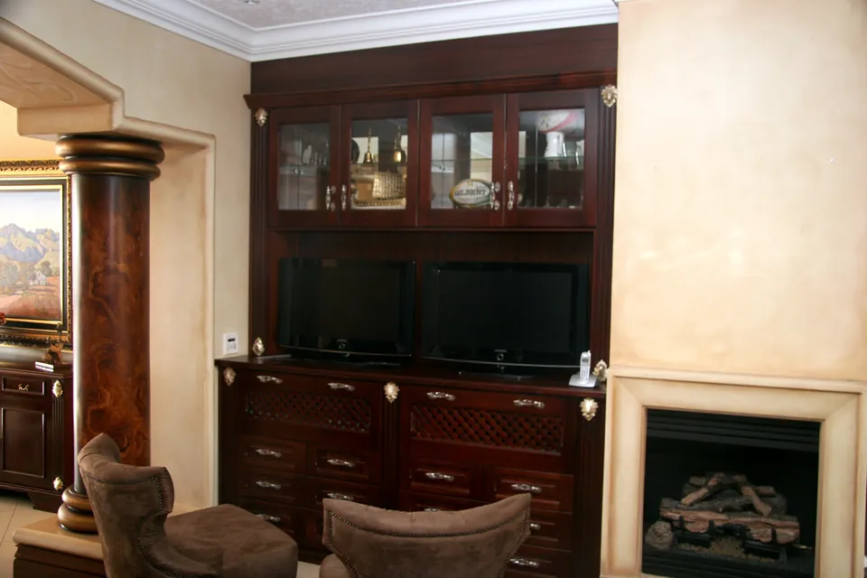 Media wall in solid African mahogany beside the fireplace