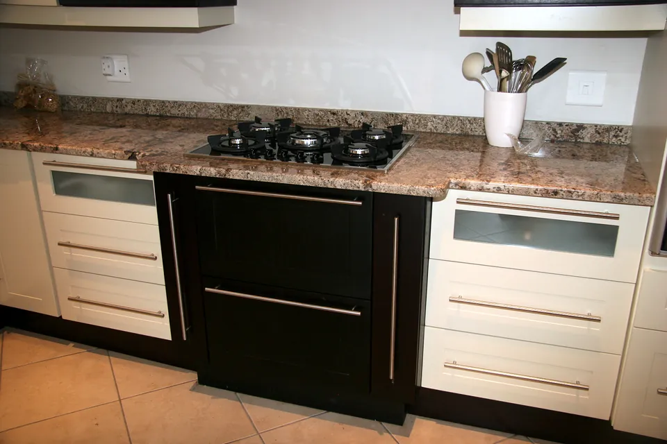 Hob over a dark pan drawer between ivory drawer banks