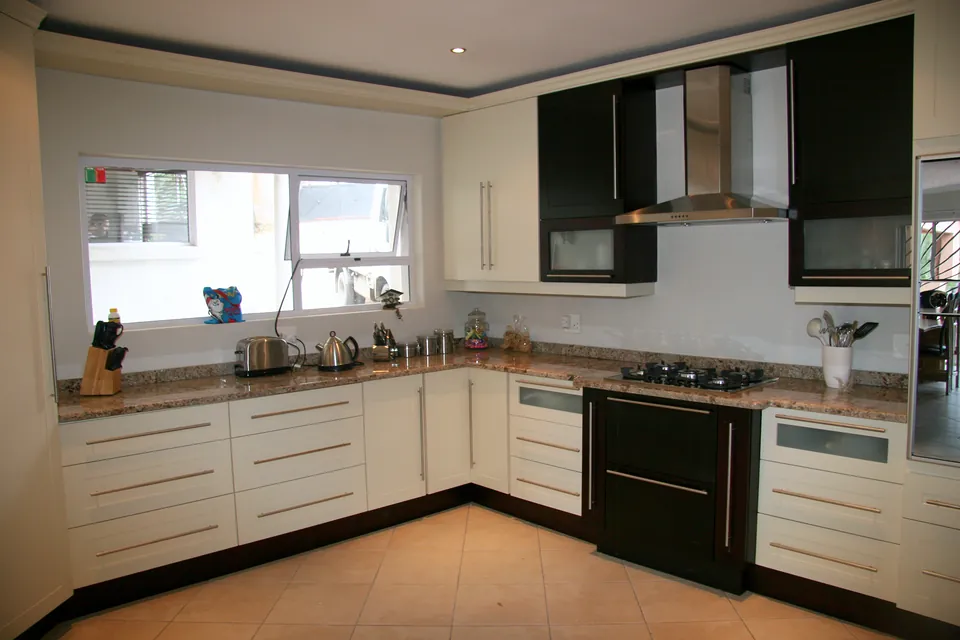 L-shaped kitchen in ivory with dark wall units and a granite top