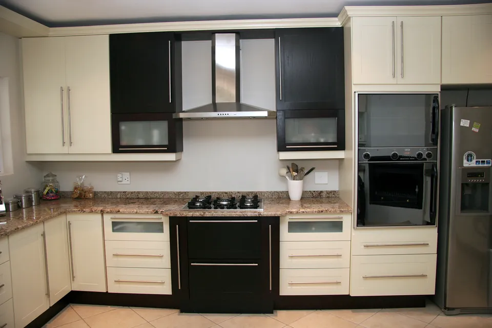 Range wall with a stainless extractor between dark glazed wall units