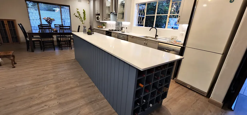 Long slate-blue island with a white top and a wine rack in its end