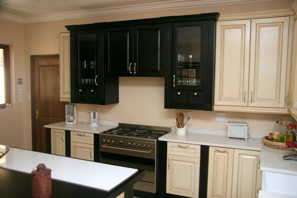 Kitchen with cream painted base units and black wall units, and a black-and-cream island